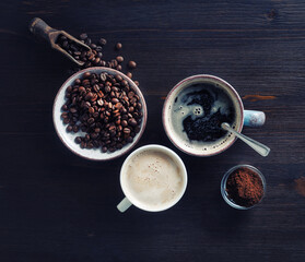 Photo of coffee cups, roasted coffee beans and ground powder on wooden table background. Top view. Flat lay.