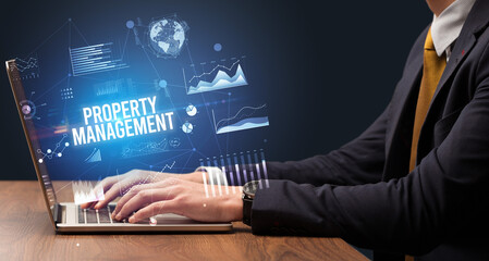 Businessman working on laptop with PROPERTY MANAGEMENT inscription, new business concept