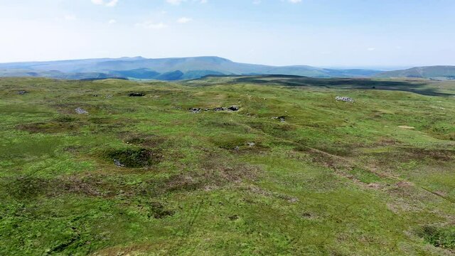 Aerial view of the entrance to the Chartist Cave with the Brecon Beacons and Pen-y-Fan mountains in the background