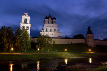 View of the night Pskov Kremlin near the city river on a summer clear day. Beautiful purple sunset over the cityscape.