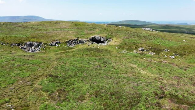Aerial view showing the entrance to an underground cave system on remote moorland (Chartist Cave, Brecon Beacons, South Wales, UK)