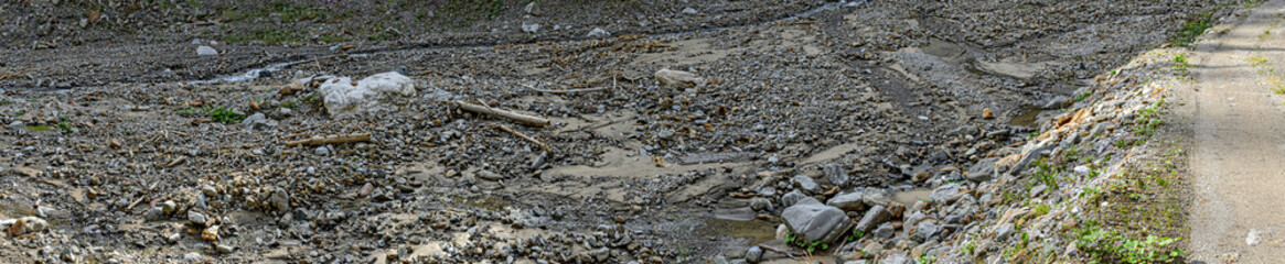 Dry bed of a mountain creek with boulders along a forest road
