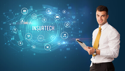 Businessman thinking in front of technology related icons and INSURTECH inscription, modern technology concept