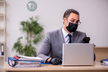 Young male employee in the office during pandemic disease