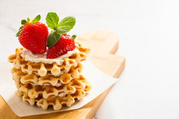 Fresh traditional belgian waffles with soft cheese and berries on a light table with copy space.