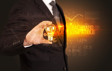 Businessman holding lightbulb with BACKWARD COMPATIBLE inscription, Business technology concept