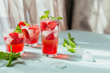 Glass of strawberry soda drink on light blue background. Summer healthy detox lemonade, cocktail or another drink background. Nonalcoholic drinks, super food, vegetarian or healthy diet concept.