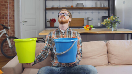 Man Using Buckets For Collecting Water Leakage From Ceiling