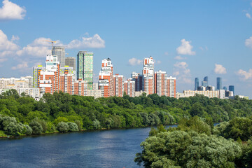 Obraz premium Panoramic view of modern residential buildings in Moscow Russia a Sunny summer day with green trees and moscow river with boat and copy space
