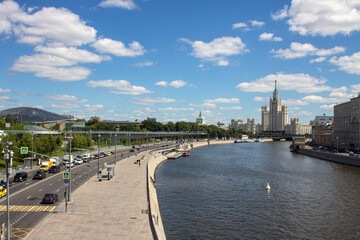 Fototapeta premium Panoramic view of the house on Kotelnicheskaya embankment and the Moscow river with pleasure boats on a clear summer day with blue sky and white clouds and copy space