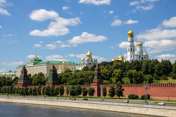 Fototapeta na wymiar Panoramic view of the historical center of Moscow Russia with the red brick Kremlin wall and the assumption Cathedral with Golden domes against a bright blue sky and space for copying