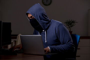 Male hacker hacking security firewall late in office