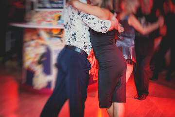 Couples dancing argentinian dance milonga in the ballroom, tango lesson in the red lights, dance...