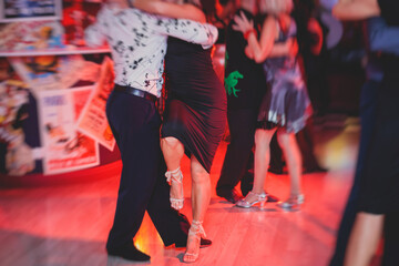 Couples dancing argentinian dance milonga in the ballroom, tango lesson in the red lights, dance...