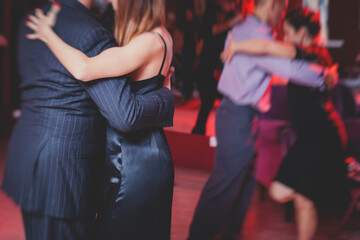 Couples dancing argentinian dance milonga in the ballroom, tango lesson in the red lights, dance...