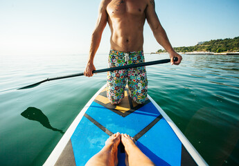 Couple stand up paddle boarding together at sunrise