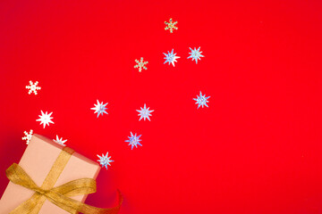 Bright red background with a festive box and gift, gold ribbon, shiny stars. New year 2021