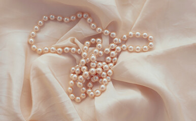 Pearl necklace on beige fabric.