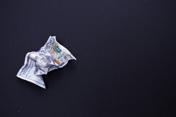 Crumpled one hundred dollar bill on a black background. The concept of the fall of the dollar as a result of the coronovirus pandemic