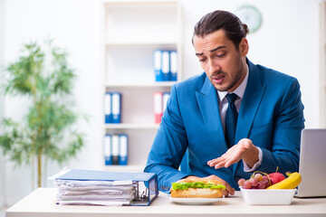 Young male employee having breakfast at workplace