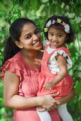 A happy south asian woman with two years old girl in spring park