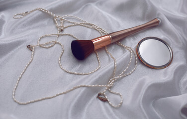 Women's accessories: makeup brush, mirror and pearls