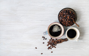 Cups of coffee and coffee beans on light wood kitchen table background. Flat lay.