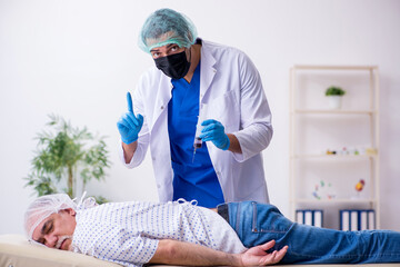 Naklejka premium Old man visiting young male intern doctor
