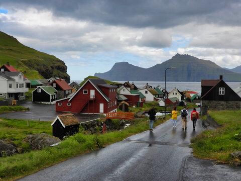 A group of tourists is walking in the rain in a small village of Gjogv, Faroe Islands.