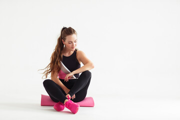 Fototapeta premium Smiling multiracial female yogi girl sit on rubber mat before yoga class, happy woman waiting for pilates training in white fitness studio. sport center banner for website header design.