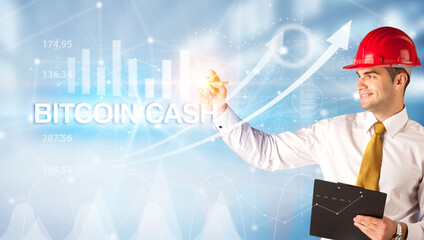 Young businessman with helmet drawing BITCOIN CASH inscription, modern business technology concept