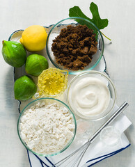 ingredients for sweet baked figs on a tray. flour, muscovado sugar, yogurt and lemon