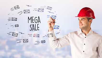 Handsome businessman with helmet drawing MEGA SALE inscription, contruction sale concept