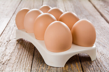 Fresh eggs in an egg tray on a wooden table