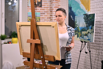 The artist works in her creative space, surrounded by paintings