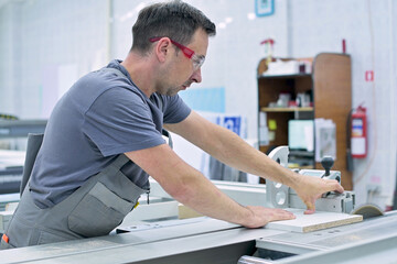 A man works in the assembly shop on a circular saw, neglecting safety requirements