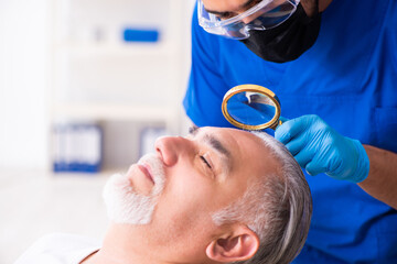 Old man visiting young male doctor in hair transplantation conce