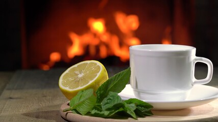 Fireplace and cup of Tea with lemon and mint on board.
