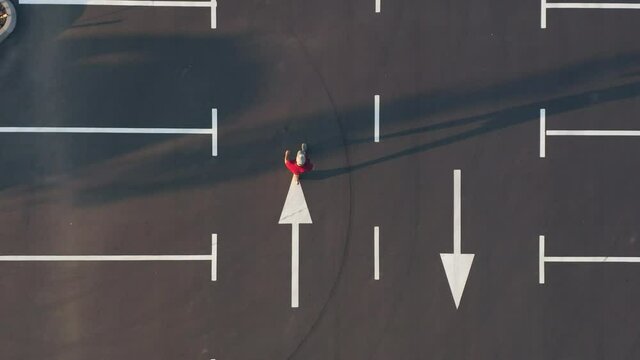 The man is walking along the empty parking lot