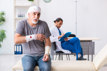 Young male doctor and old patient in first aid concept