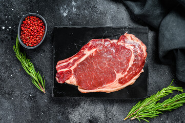 Fototapeta na wymiar Raw cowboy steak. Marble beef meat on the bone ribeye. Black background. Top view