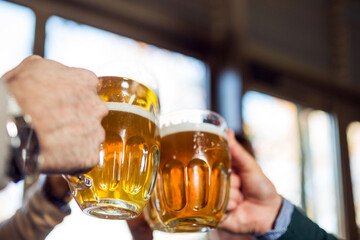 Friends clinking glasses with beer in beer pub