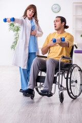 Fototapeta na wymiar Young male patient in wheel-chair doing physical exercises
