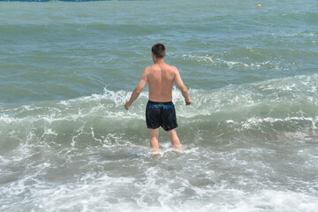 Fototapeta premium average waves on the sea reach the shore with foam and crash on the rocks with a noise