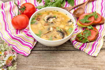 Potato soup with mushrooms for vegetarians on a wooden table and a pink napkin.