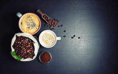 Coffee cups with roasted coffee beans on black kitchen table background. Copy space for your text. Top view. Flat lay.