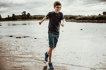 young boy enjoy a cloudy day at mud flat run away from raising water