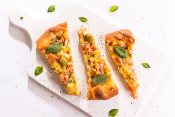 Três pedaços de pizza portuguesa com folhas de manjericão sobre a tábua branca