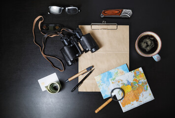 TraTravel plan background. Ready for the trip. Essential travel accessories on black table background. Flat lay.