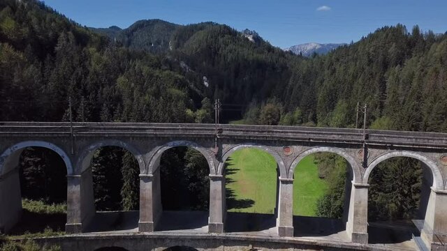 Aerial view of passenger train rides on famous Kalte Rinne Viaduct on historical Semmering mountain railway (Semmeringbahn), Lower Austria.